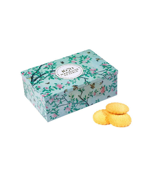 Caja metálica de galletas de mantequilla en un jardín.